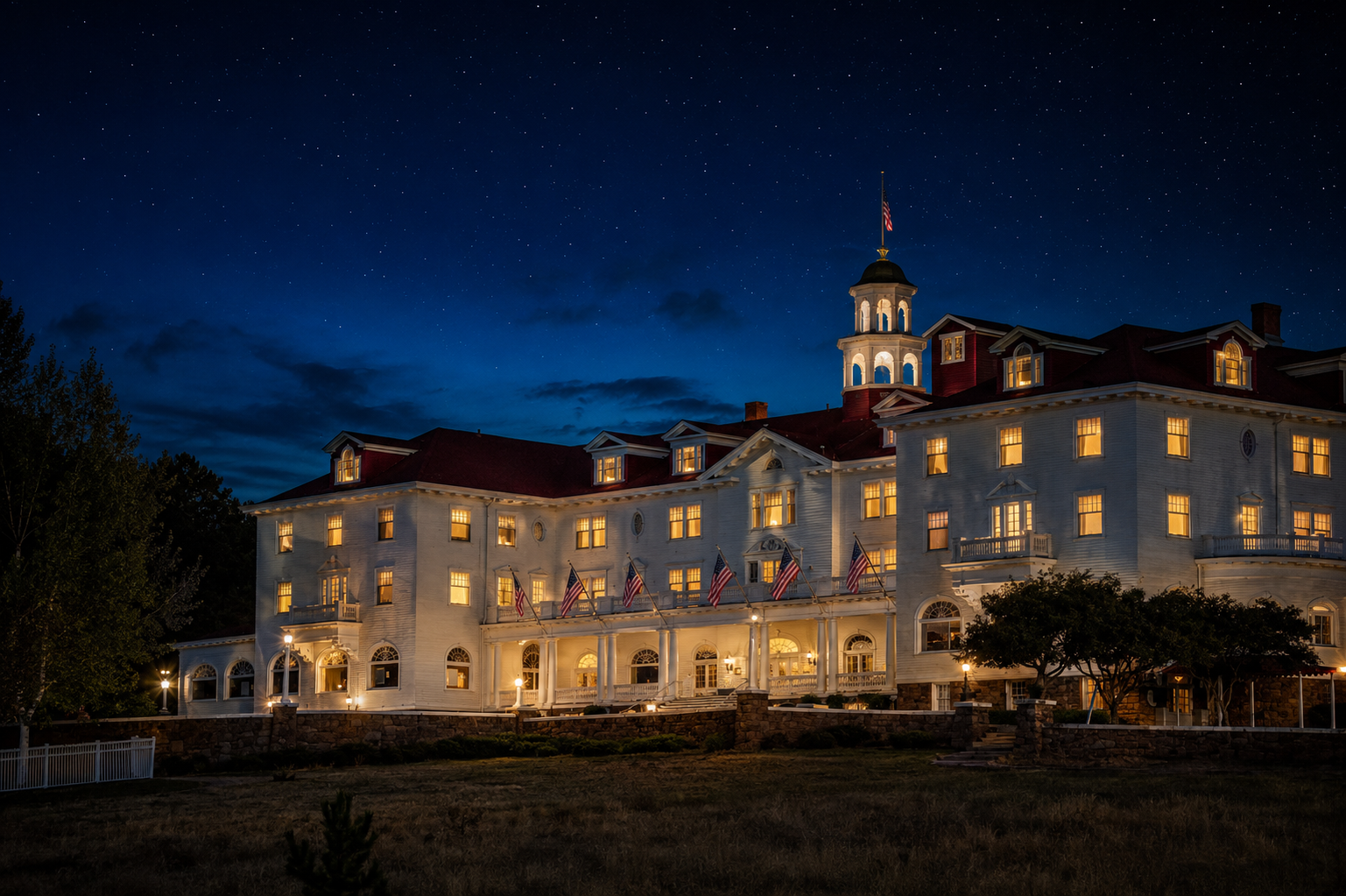 Historic hotel exterior at night, warm lights glowing in the windows
